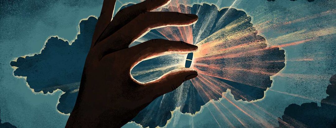 A hand in shadow handles up a pill that is illuminated from behind, emitting rays of light.